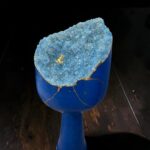 Blue ceramic goblet with a rough, blue geode inside showing crystalline texture and gold crack lines along the rim edge