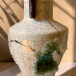 Decorative crackle-glaze ceramic vase with a dark brown neck accent and a green crystal cluster attached to its side.