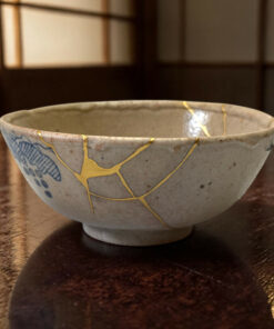 Close-up of a ceramic bowl with blue designs and gold crackle lines on a dark wooden table