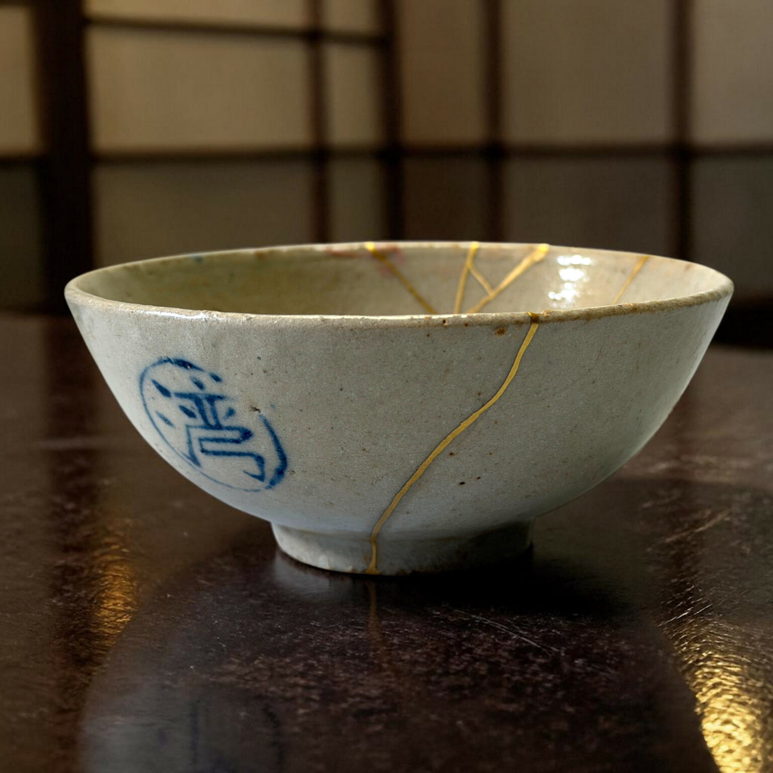 Close-up of a light ceramic bowl with a gold crackle glaze on its rim, resting on a dark wooden surface, with blue decorative accents on the side.