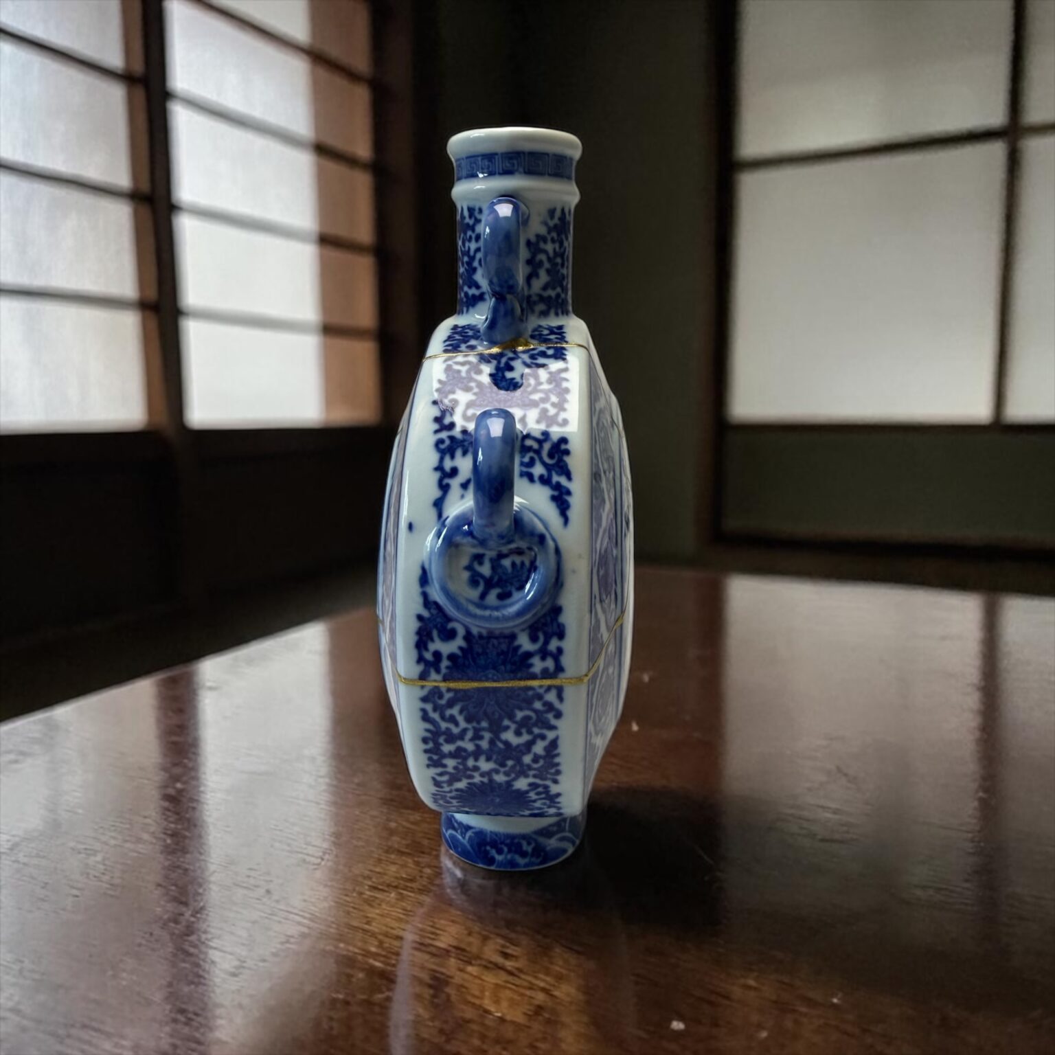 Close-up of a blue-and-white porcelain vase with intricate floral patterns on a wooden table.