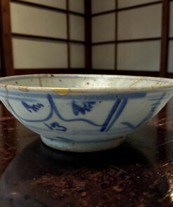 Blue and white ceramic bowl on a dark wooden table, photographed from the side.