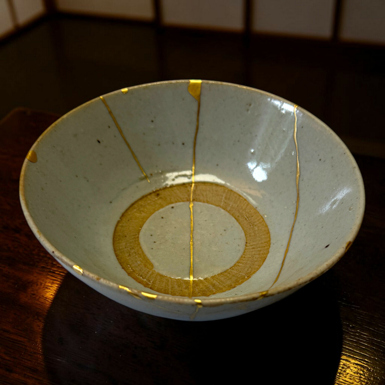 Close-up of a pale blue ceramic plate with gold decorative lines on a dark wooden table left and center-aligned in the frame.