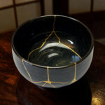 Black plastic bucket seen from above with a yellow string draped along the rim, on a wooden surface