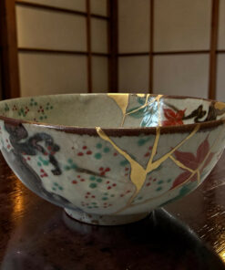 Stacked ceramic bowls with blue, red, and gold floral patterns on a dark wooden table that’s visible in the background.