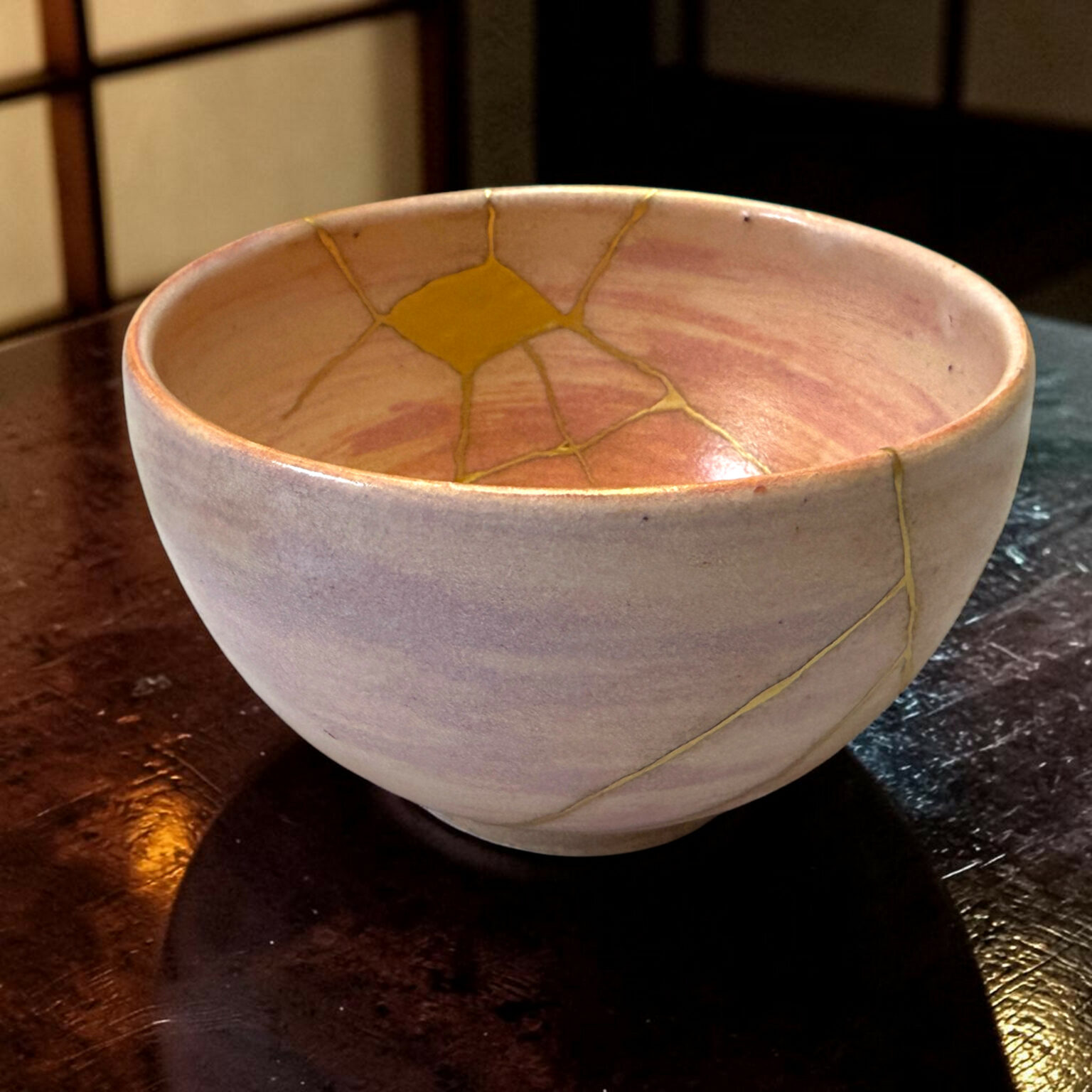 Close-up of a light gray ceramic bowl showing yellow crackle glaze lines inside and along its rim, resting on a dark wooden table in warm lighting.