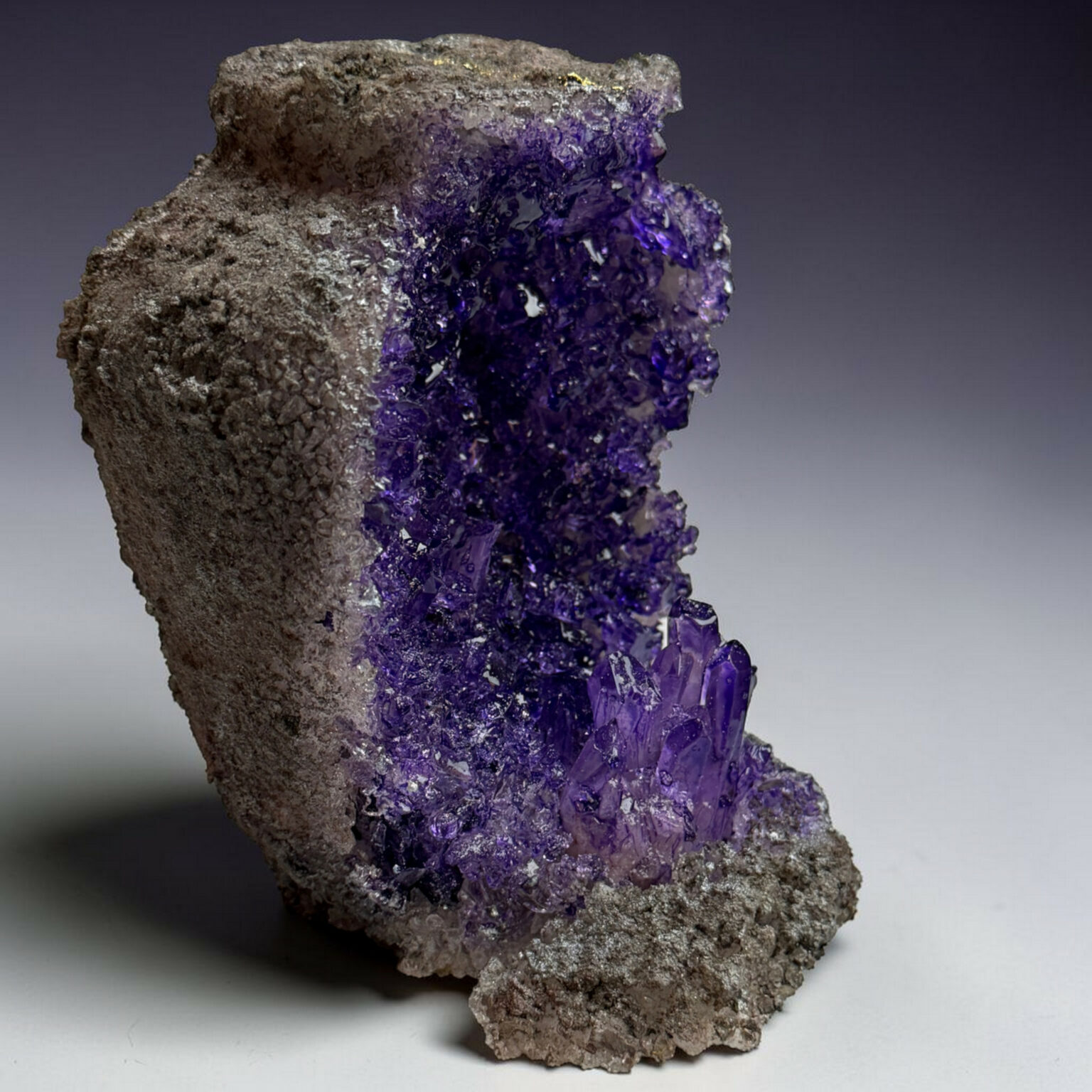Purple amethyst crystal cluster growing from a rough brown rock surface.