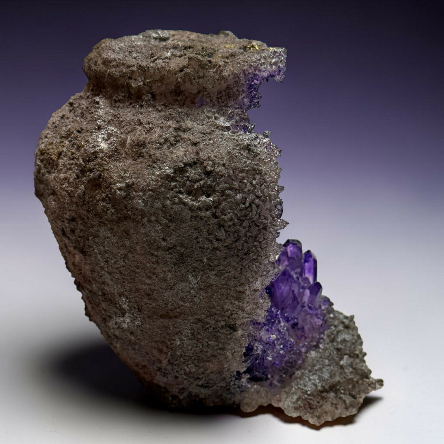 Rough brown rock with jagged purple amethyst crystals along one edge.