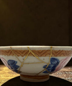 Ceramic hanging bowl with blue floral patterns and yellow cords, resting on a wooden surface.