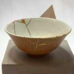 Close-up of a ceramic bowl with gold-veined glaze on a light surface.
