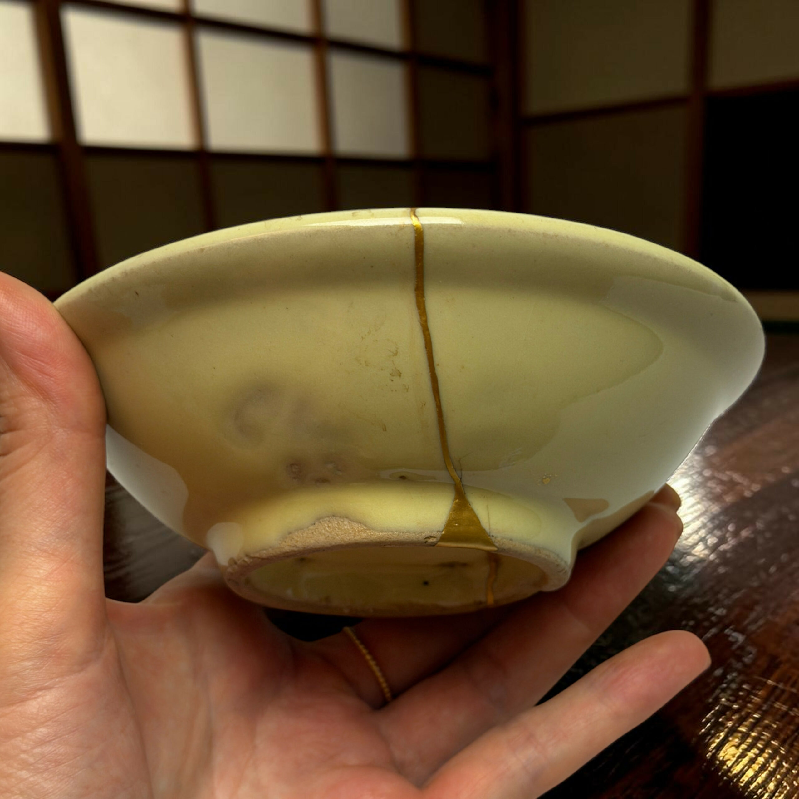 Person holds a pale green egg-shaped object with a vertical seam and astring wrapped around it, fingers visible in the foreground.