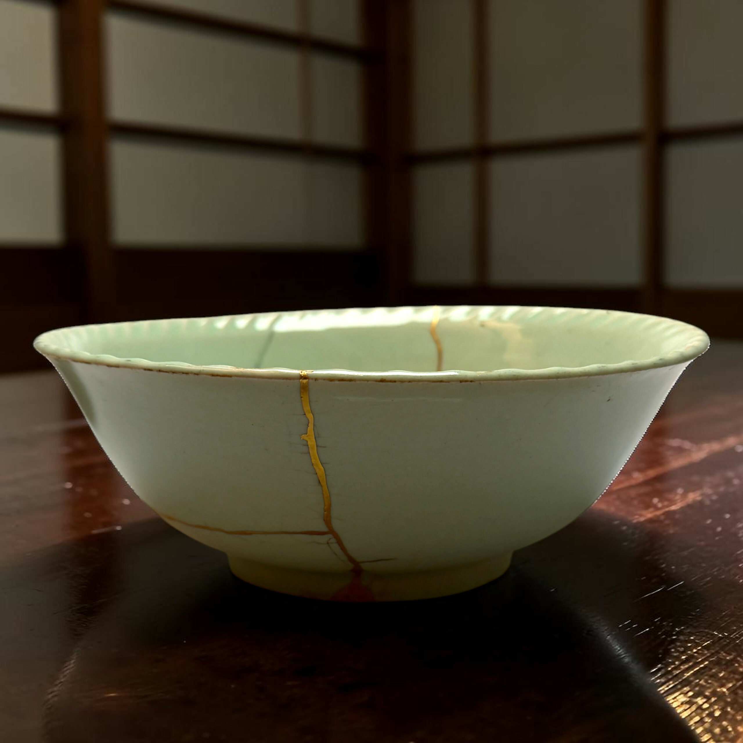 Close-up of a white ceramic bowl with a gold vertical line design, resting on a dark wooden table.