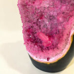 Close-up of a pink crystal sugar-dusted donut on a light background.