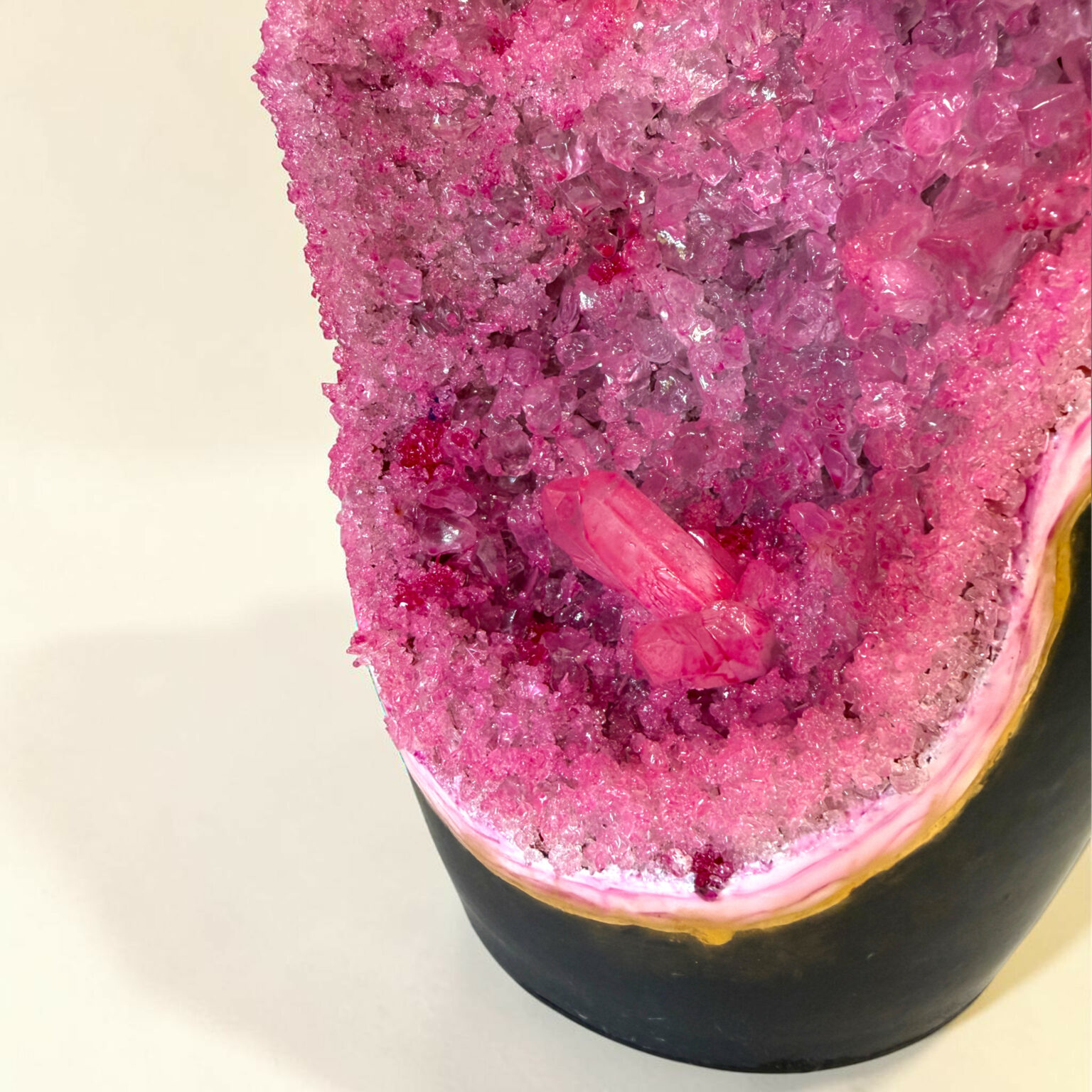 Close-up of a pink crystal sugar-dusted donut on a light background.