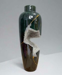 Tall ceramic vase with dark green glaze, brown base, and a white crystalline crack running down the side.