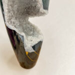 Close-up of a purple ceramic vase with white crystalline mineral growth on its surface.