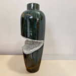 Tall dark green marbled vase with a band of white crystalline material wrapped around its lower half and an orange string tied around it.