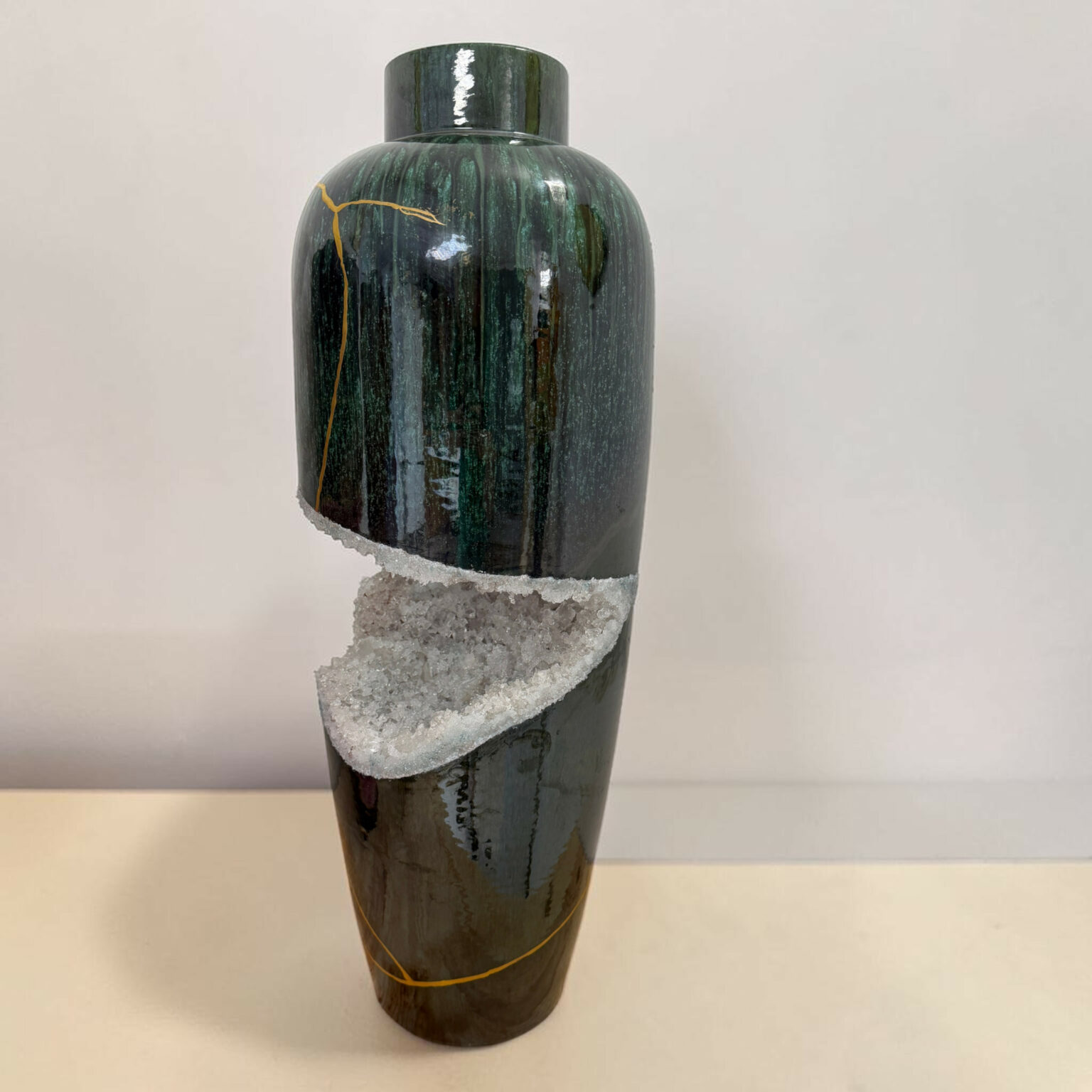 Tall dark green marbled vase with a band of white crystalline material wrapped around its lower half and an orange string tied around it.