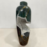 Dark green ceramic vase with gold veins and a jagged cluster of crystals along its surface.