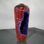 Tall red ceramic vase with gold crackle lines and a large purple torn panel exposing the interior edge.