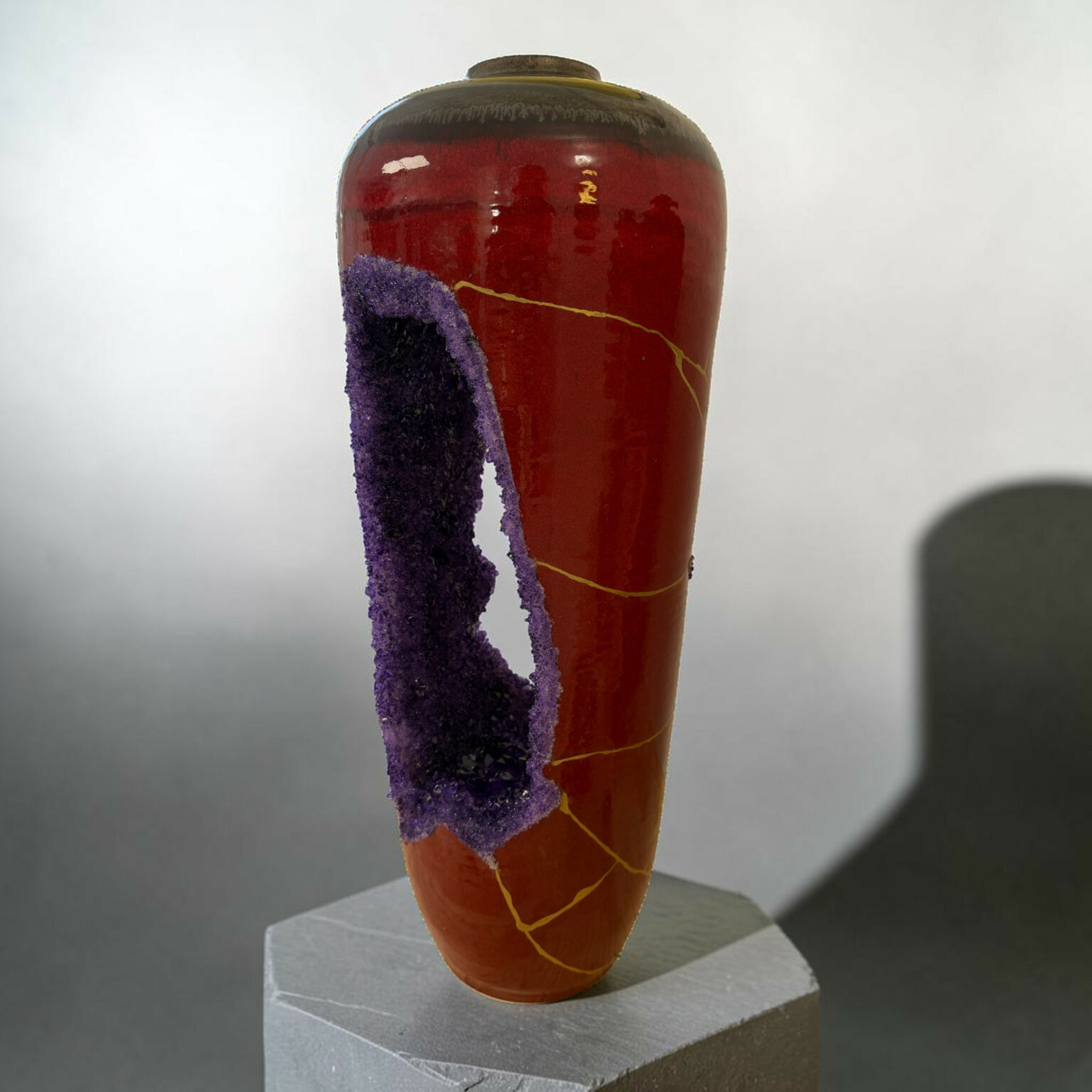 Close-up of a glossy red ceramic vase with purple crystalline formations along its side, placed on a pedestal.